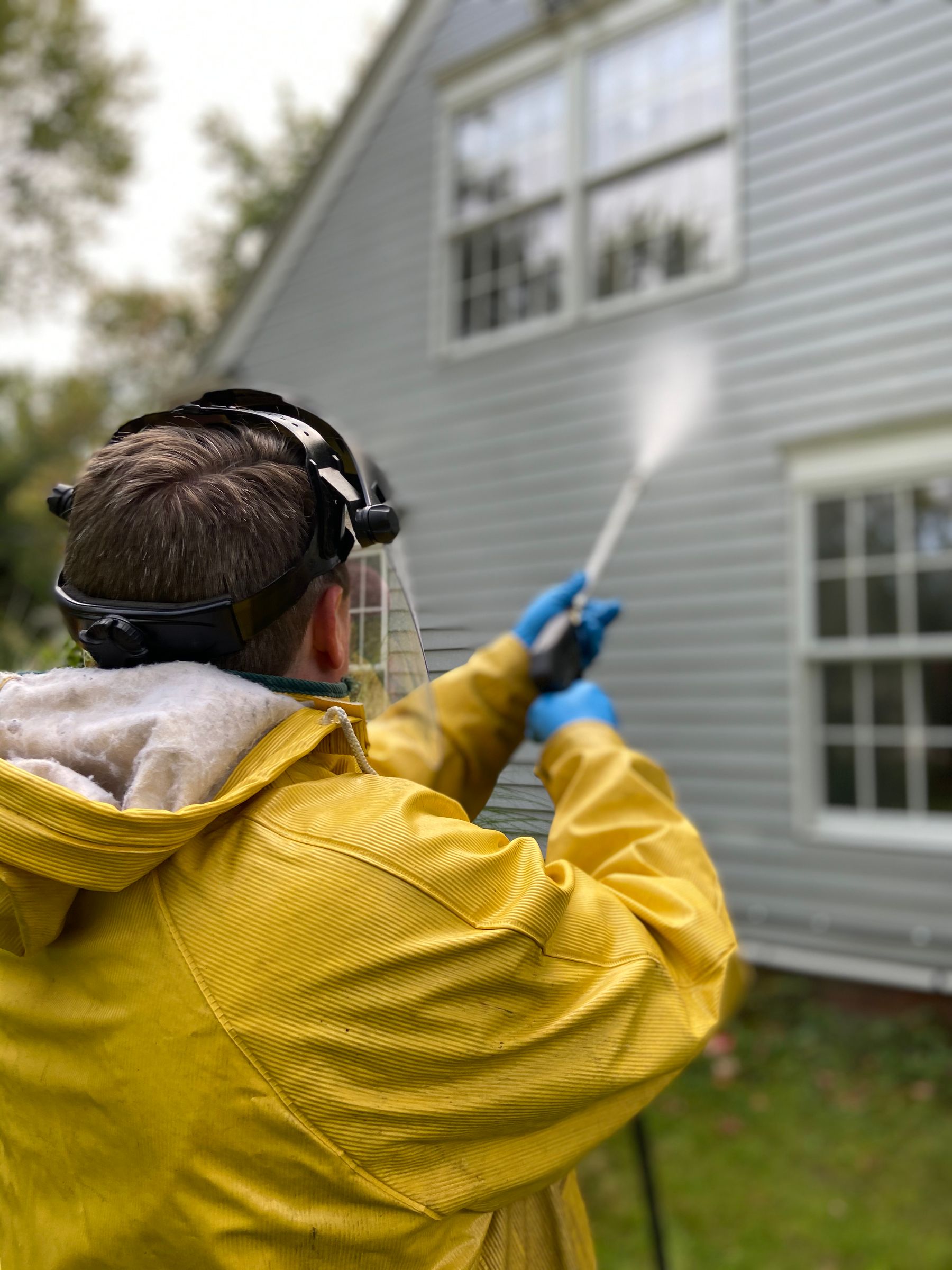 Professional washing the exterior siding of a home